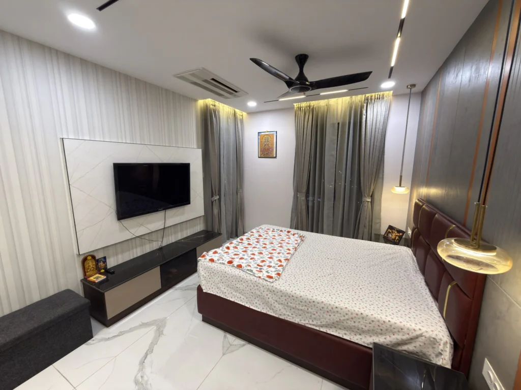 Modern bedroom with a small attached TV unit, comfortable bed, and contemporary interior design.