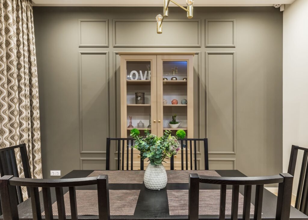 Table with chairs near beige cupboard with utensil in dining room with modern interior